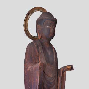 頭部には金色の円形の光背が取り付けられ、衣をまとい左手に小さな器を持った茶色がかった木材の質感がはっきりとわかる仏像の写真