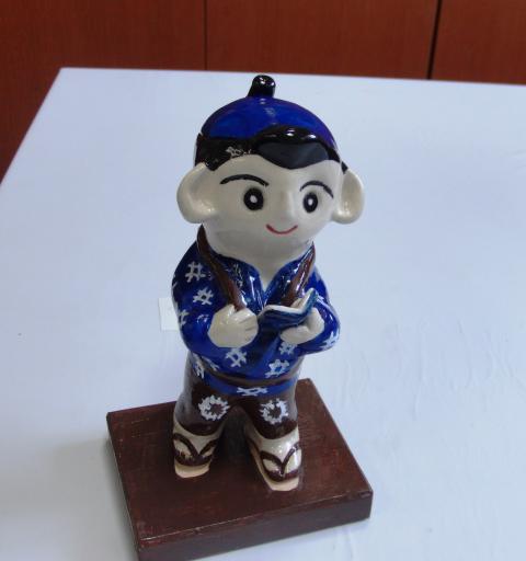 木製の四角い台座に乗った焼きもので作られた青い服を着たミニ二宮金次郎像の写真