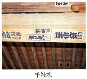 木造の建物の木の柱に、複数の千社札が貼られている様子の写真