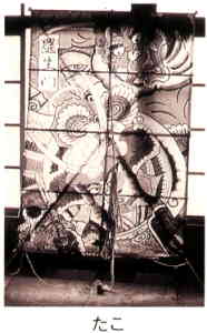 兜をかぶった武者と鬼の絵が描かれた大きなたこの白黒写真のしたに「たこ」と書かれた画像