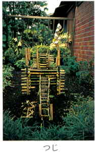 たくさんの細い竹を複雑に組み合わせた、辻が草木が茂った庭に置かれている写真の下に「つじ」と書かれた画像