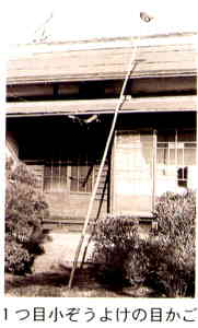 木造の建物の前に屋根の上までのびた竿が立てかけられ、竿の先にはかごがついている様子がわかる白黒写真の下に「1つ目小ぞうよけの目かご」と書かれた画像