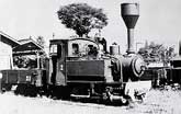 円錐形の大きな煙突を持つ蒸気機関車が場所で停車している様子を写した古いモノクロ写真