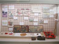 白い格子状のボードやその下の台に、絵画や古文書、道具などが多数展示された歴史資料コーナーの写真