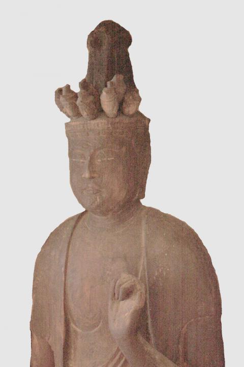 頭上に複数の小さな顔が乗った木彫りの十一面観音菩薩立像の写真