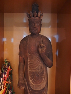 ガラスケースの中に安置された、頭上に複数の小さな顔が乗った木彫りの十一面観音菩薩立像の写真