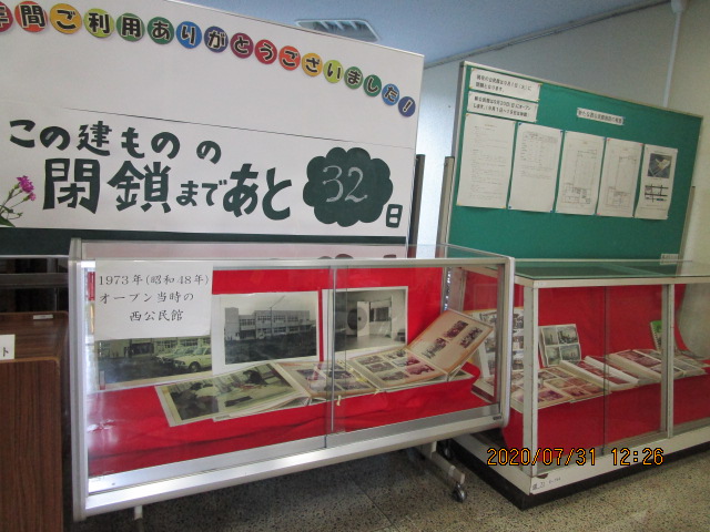 建物の閉鎖まで32日を示す掲示と1973年オープン当時の西公民館の写真や資料を展示した赤い台のガラスケースが並ぶ展示コーナーの写真