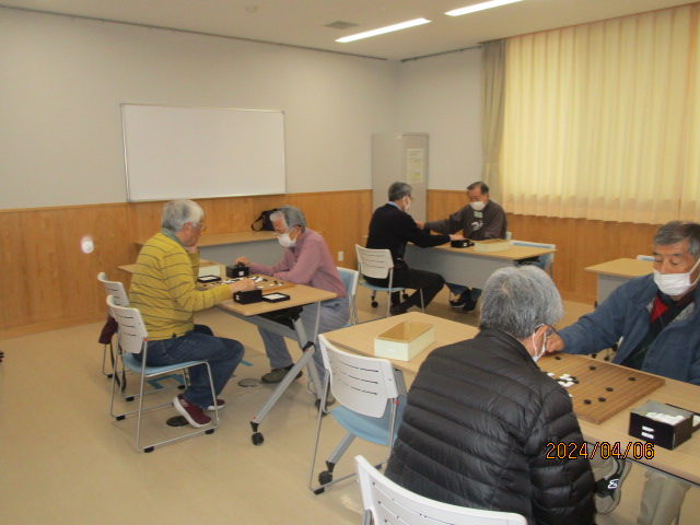 数人が机に向かい合って座り、囲碁の盤を囲んで楽しそうに対局している様子を写した、囲碁交流会の写真