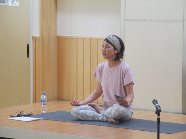 床に敷かれたヨガマットの上に胡坐をかいて座っている伊藤由美先生の写真