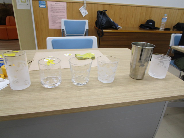 木目調のテーブルの上に、模様が施された透明なグラスが5個とステンレス製のタンブラーが1個、合計6個のコップが並べられている室内を捉えた写真