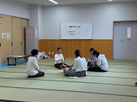 畳敷きの和室で、中央に座っている数人の女性たちが、小さな赤ちゃんをあやしたり、何かを教えたりしながら、和気藹々とした雰囲気で交流している様子の写真