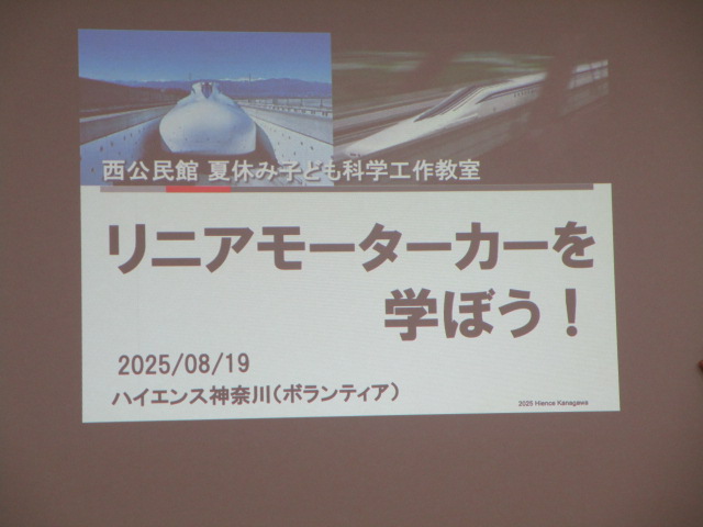 プロジェクターで映し出されたスライドで、「リニアモーターカーを学ぼう！」という大きな文字が中央に表示されており、上部には走行中のリニアモーターカーの写真が添えられている、科学教室の案内の写真
