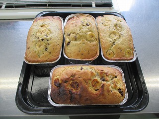 オーブンで焼き上がったバナナの輪切りがトッピングされた手作りのバナナチョコケーキが、銀の焼き型に入って4本並んでいる写真