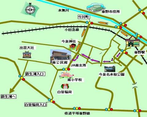 淡い緑色の背景に、秦野市役所、JA南支所、今泉神社、出雲大社などの主要施設が建物イラストで示され、道路が茶色と青の線で描かれ、赤丸の交差点や方向矢印で案内された地図の画像