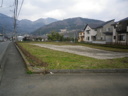 アスファルト道路の角地にある、草原の中央に駐車スペースが整備された第1駐車場の写真