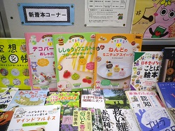 本の展示スペースに、フェルトやミニチュアスイーツの作り方など、手芸や工作関連の書籍が平積みされている「新着本コーナー」の写真