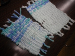 木目調のテーブルの上に置かれた、2種類の手織りされた四角いコースターの写真