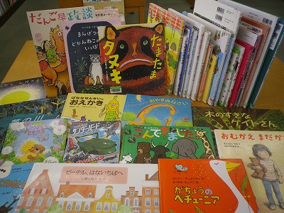 動物や乗り物、キャラクターなどが描かれた様々な色とデザインの表紙を持つ絵本が平積みで展示されている、絵本の新着本コーナーの写真