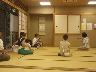 和室で赤ちゃんを抱えたお母さんたちが、講師から絵本の読み聞かせをしてもらっており、畳の部屋で子育てに関するイベントが開催されている写真
