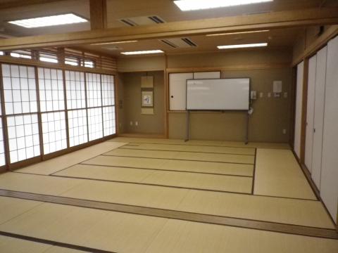 障子窓があり、奥の壁際には白いホワイトボードが置かれた広い和室の写真