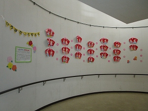 ひな人形とピンクの星形の飾りが白い曲面の壁に多数貼られている広い展示場の様子の写真