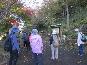 山のふもとで大人数名が説明を受けている