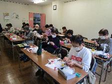 大人十数名が教室の机で縫い物をしている