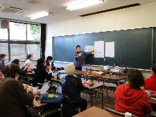 大人十数名が黒板に向かって、黒板に張った資料により説明を受けている