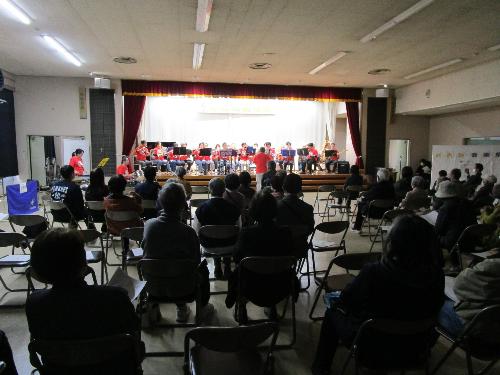 ステージ上で吹奏楽団が演奏している様子を観客席から撮影した写真