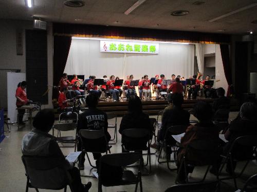 ステージ上で吹奏楽団が演奏している様子を観客席から撮影した写真