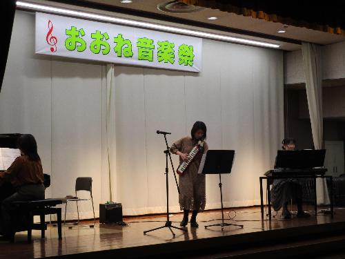 ステージ上で女性3名がそれぞれピアノ、キーボード、ピアニカ演奏を披露している