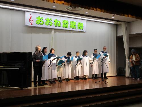 子どもを含む数名の白いガウンを着た聖歌隊がコーラスを披露している