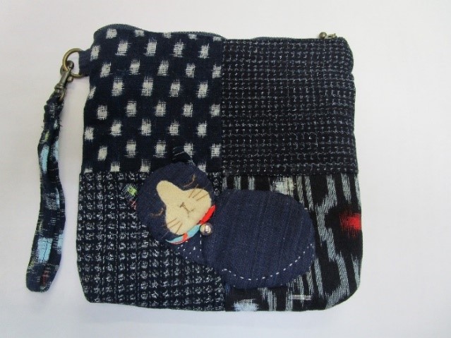 複数の布を縫い合わせたバッグで猫の飾りが縫い付けてある