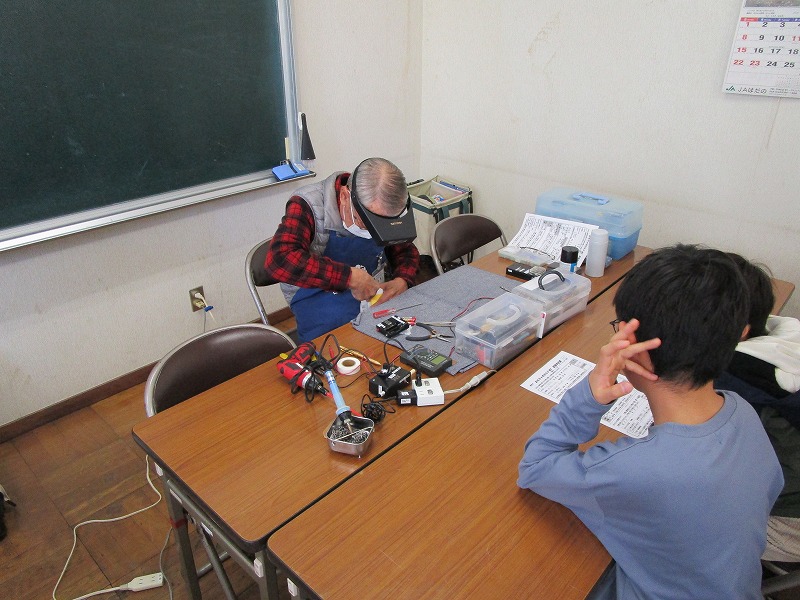 おもちゃの修理をしている様子と、それを子どもが見ている。