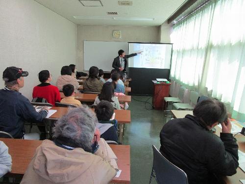講師がスクリーンに映した資料で受講者十数人に対して説明をしている様子