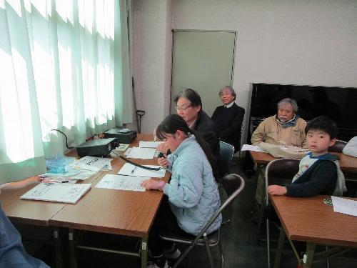 女の子が無線機のマイクに向かって話しかけているのを、数名の受講者が見ている様子