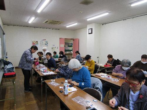 十数人の女性が机の上で縫物をしている様子