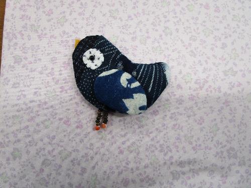 和布で縫い上げた鳥のブローチの写真
