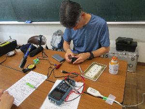 おもちゃの電車を修理している様子。机上にはいろいろな修理機材が置かれている。