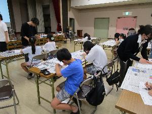 複数のテーブルそれぞれで、子ども達がプラスチック板に絵を描いている様子