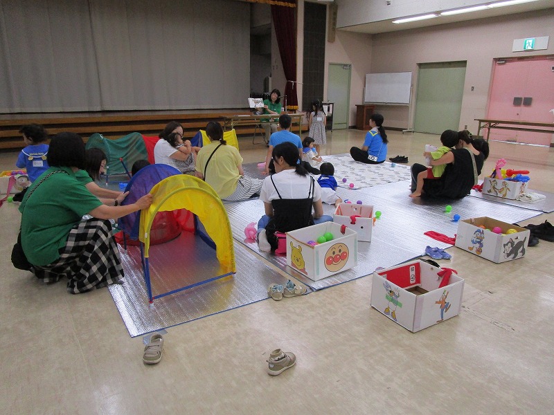 数組の親子が床に敷かれたシートに座って、遊んだり休憩している様子