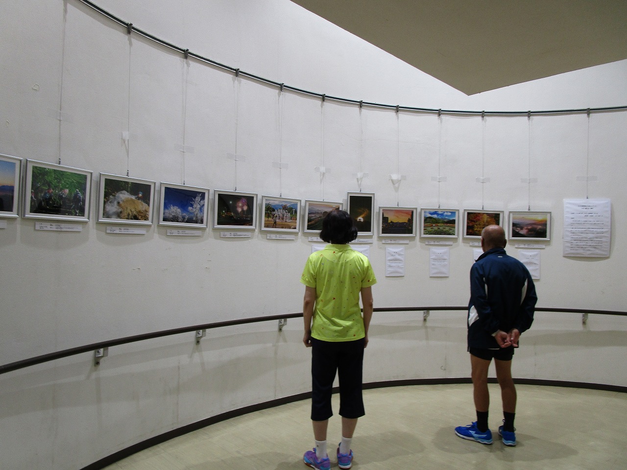 壁に展示された写真を男女二人が観覧している様子