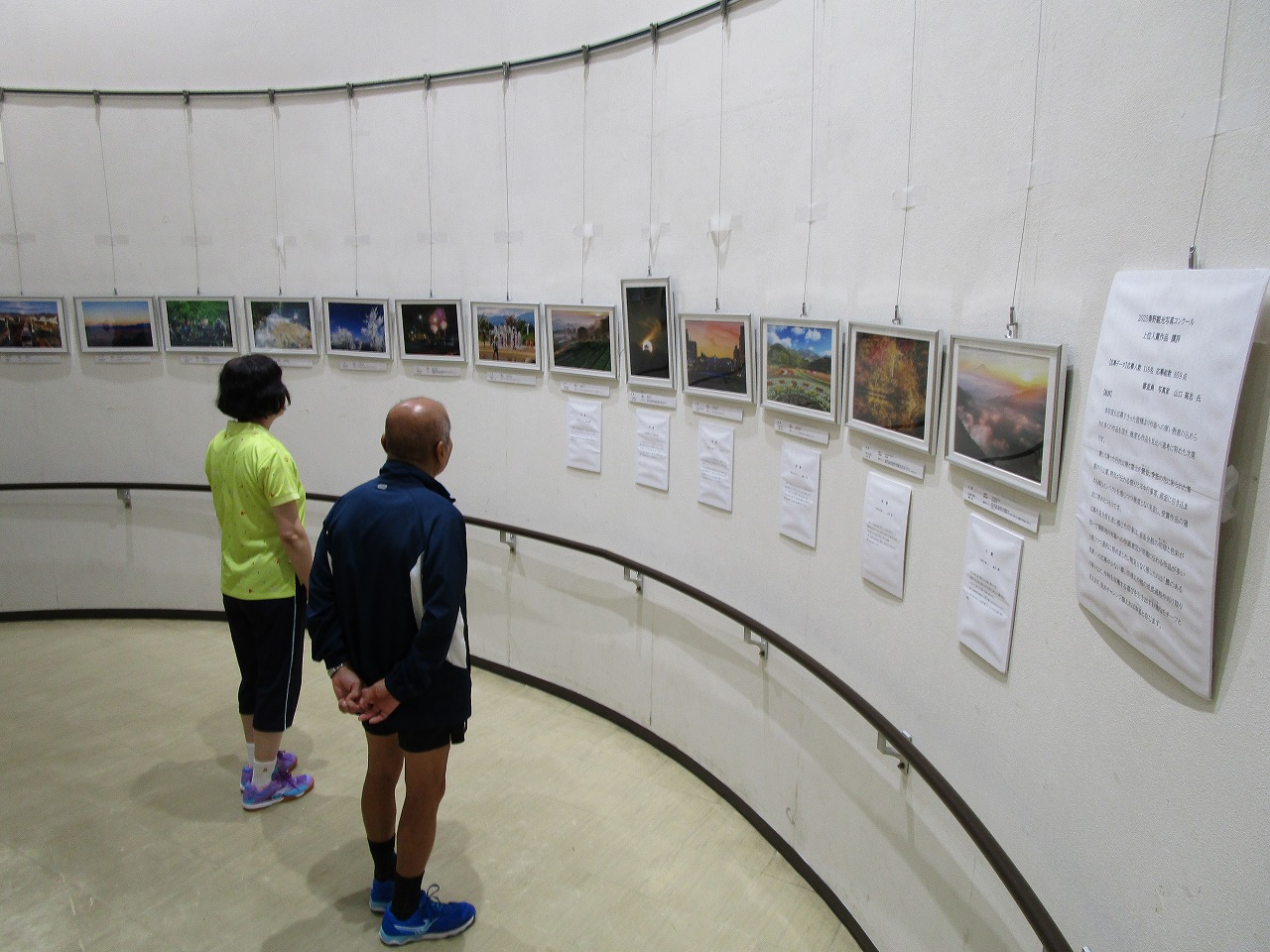 壁に展示されている写真を男女二人が鑑賞している様子