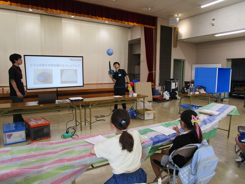 ブロワーで風船を空中に止めている実験を子供たちが見ている様子