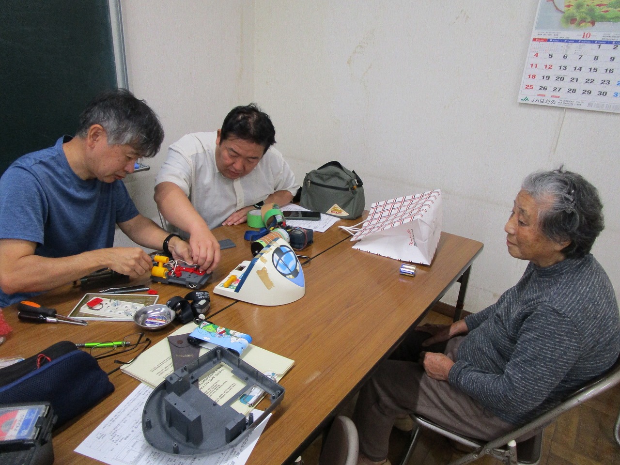 壊れたおもちゃを直しているのをおばあさんが見ている様子