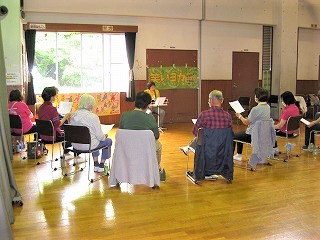 椅子に座った数名の受講者が、前方で譜面台を挟んで対面する講師の指導を仰いでいる様子を写した写真