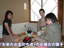 和室の畳の上に正座で座る3人の女性が写っており、中央の着物姿の女性がお茶を点てる様子を見守りながら、手前の女性が抹茶碗を持って笑顔を見せている写真