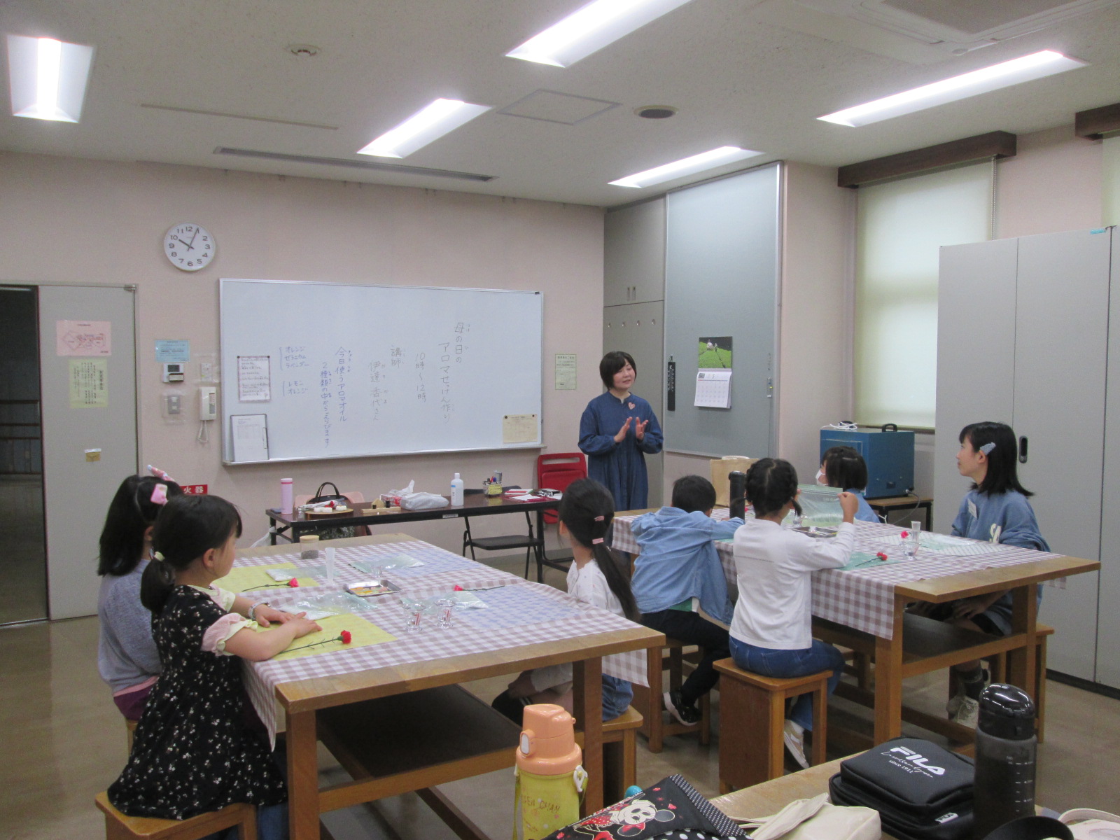 教室内で複数の子供たちがテーブルに座り、前に立つ先生が説明をしている様子を写した、学習活動の様子の写真