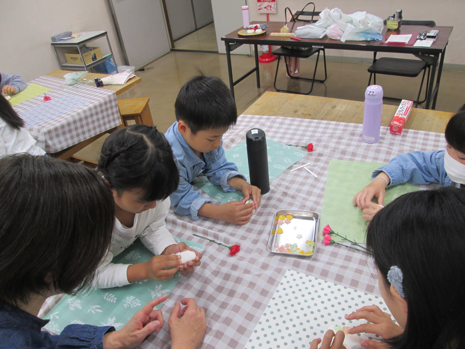 子どもたちがテーブルを囲みながら、紙や道具を使って手作業をしている様子を写した写真