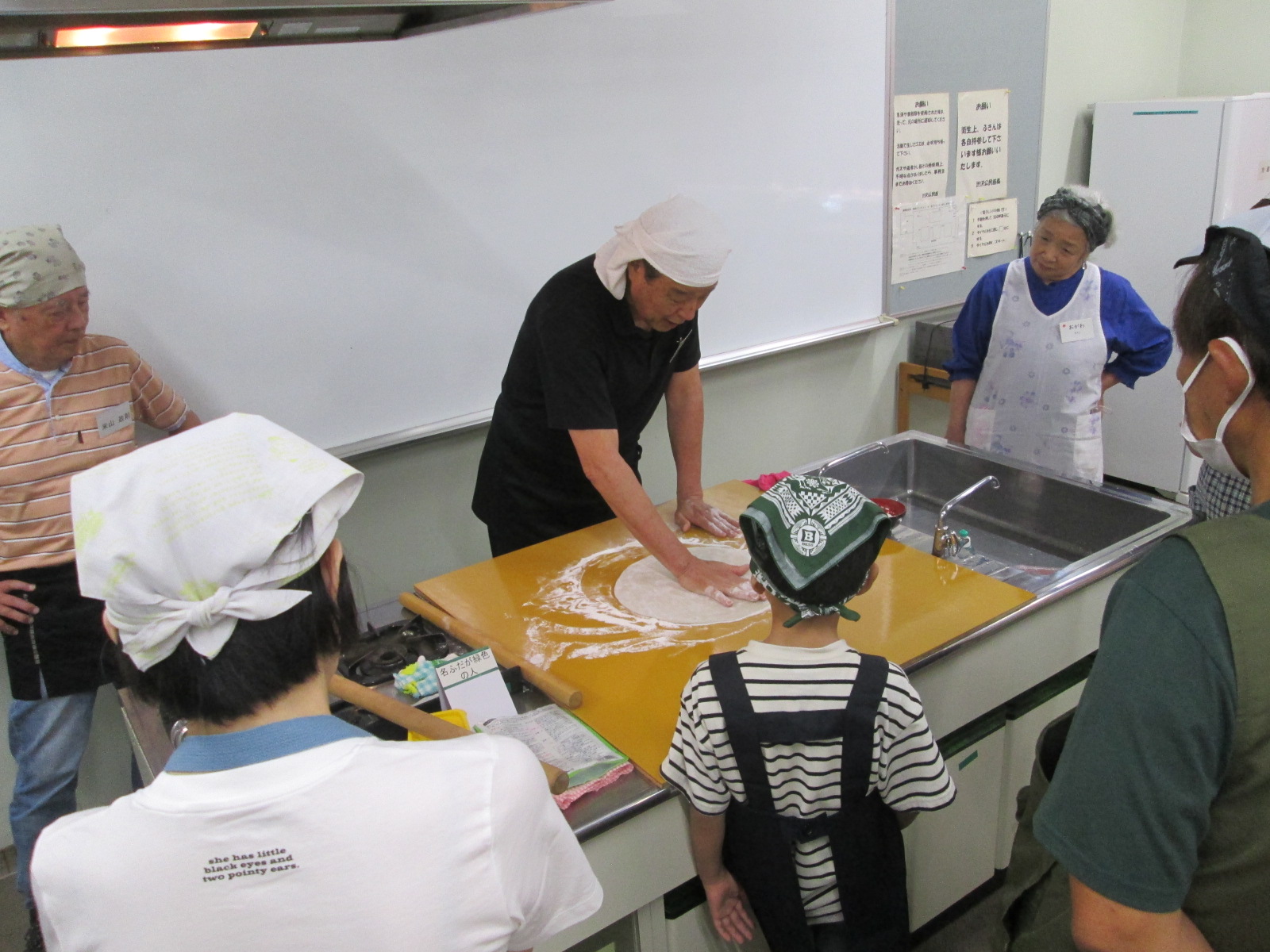 料理教室の中で、参加者がそば粉をこねてそば打ちをしている様子を写した写真